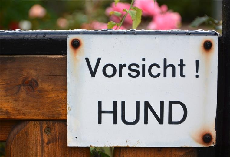 Biss in den Po: Kann ein Jogger was dafür? „Vorsicht! Hund“ steht an einem Gartenzaun. Der Halter ist trotzdem verantwortlich für sein Tier.