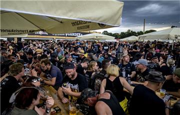 Während die Wacken-Besucher beim Auftritt der Feuerwehrkapelle in einem Biergarten feiern, ziehen Gewitterwolken vorbei. 