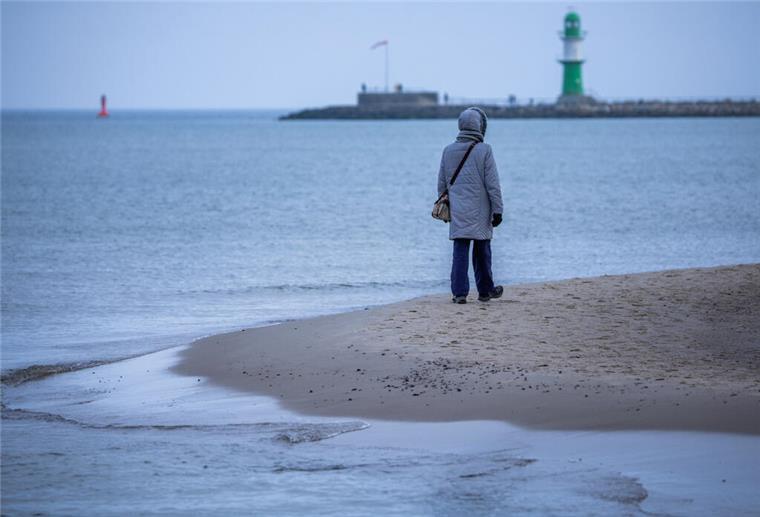 Erste Winterbilanz: So krass unterscheidet sich das Wetter im Vergleich zu früher Eine Person steht am Strand vor dem Meer und trägt eine dicke Winterjacke. Der Winter 2024/25 war im Nordwesten außergewöhnlich mild.