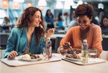Zwei Frauen sitzen bei Ikea an einem Tisch und essen und lachen. In den Ikea-Restaurants gibt es freitags und sonnabends Hauptgerichte zum halben Preis – plus Einkaufsgutschein fürs Einrichtungshaus.