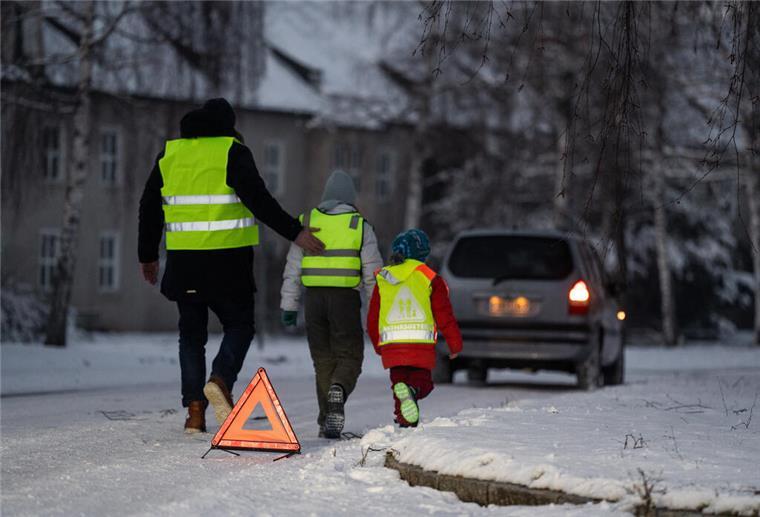 Warnwesten im Test: Viele Modelle bieten keinen ausreichenden Schutz Schnee auf Straße Menschen tragen Warnwesten