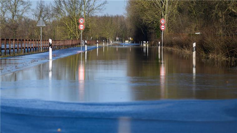 Wasser der über die Ufer getretenen Leine fließt über eine Straße.
