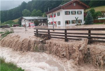 Wasser fließt über einen Platz vor einem Haus.