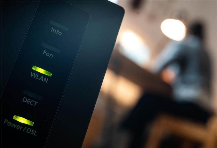 Stromkosten senken: Router nachts ausschalten Eine Frau arbeitet im Home Office. Im Vordergrund steht ein Router, auf dem die LED für W-Lan und DSL leuchten.