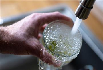 Tinkwasser läuft aus dem Wasserhahn in einer Küche in ein Glas mit Limettenstücken