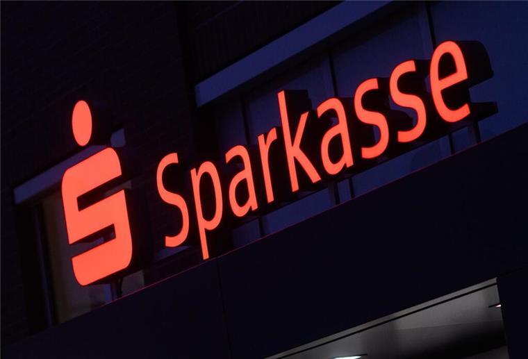 Ein Schriftzug der Sparkasse leuchtet an einer Filiale. Aktuell sind Sparkassen-Kunden im Visier von Betrügern. 