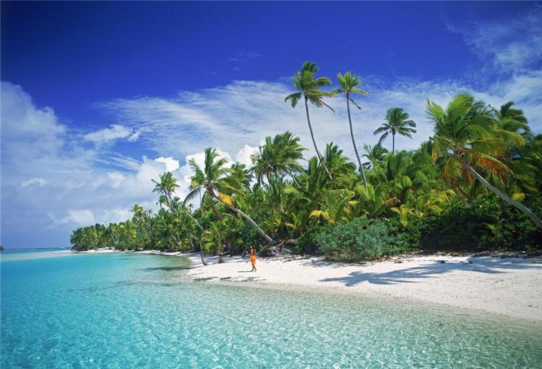 Eine Frau geht am Sandstrand von Aitutaki entlang, einer der Cook Inseln.