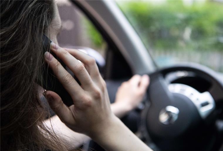  Eine Frau sitzt mit Handy am Steuer 