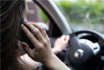  Eine Frau sitzt mit Handy am Steuer 