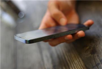 Ein junger Mann hält ein Smartphone.