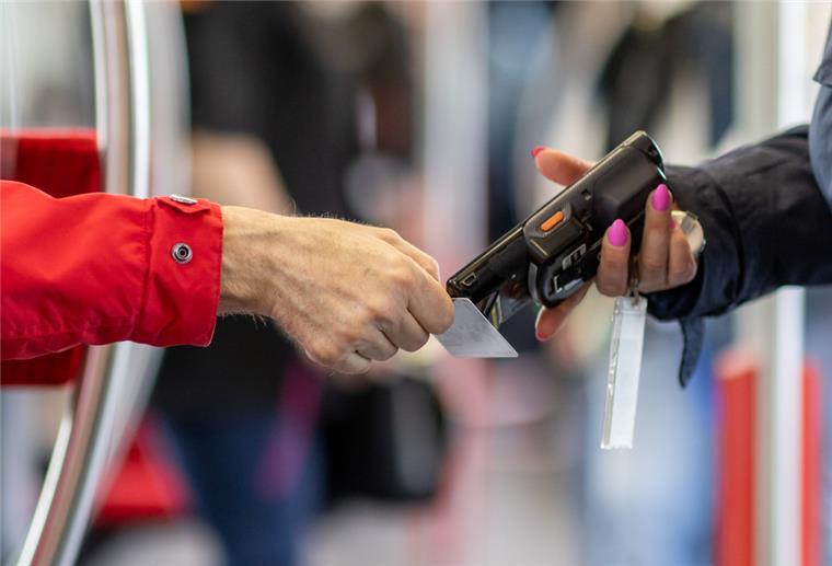 Eine Fahrkartenkontrolleurin (r) kontrolliert mit einem elektronischen Lesegerät den Fahrschein von einem Fahrgast