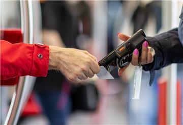 Eine Fahrkartenkontrolleurin (r) kontrolliert mit einem elektronischen Lesegerät den Fahrschein von einem Fahrgast