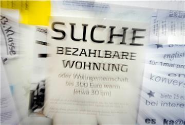 Eine Suchanzeige für eine "bezahlbare Wohnung" hängt an einem schwarzen Brett.