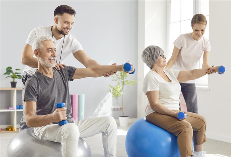 Reha nach Maß: Wie Versicherte ihre Mitbestimmung nutzen können Glückliche Senioren bei einer Reha mit zwei Fitnessexperten. Wer eine Reha plant, hat Mitspracherecht – bei Ort, Zeitpunkt und Klinik. Wichtig ist, dies direkt im Antrag klar anzugeben.