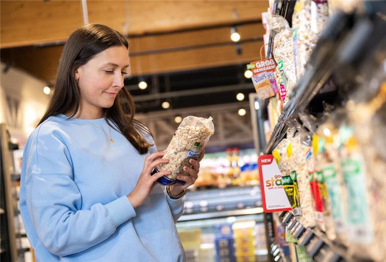 So lässt sich beim Einkauf von Lebensmitteln bares Geld sparen Eine Frau im Supermarkt hält eine Packung in der Hand. Wer es schlau anstellt, kann im Supermarkt jede Menge bares Geld sparen.