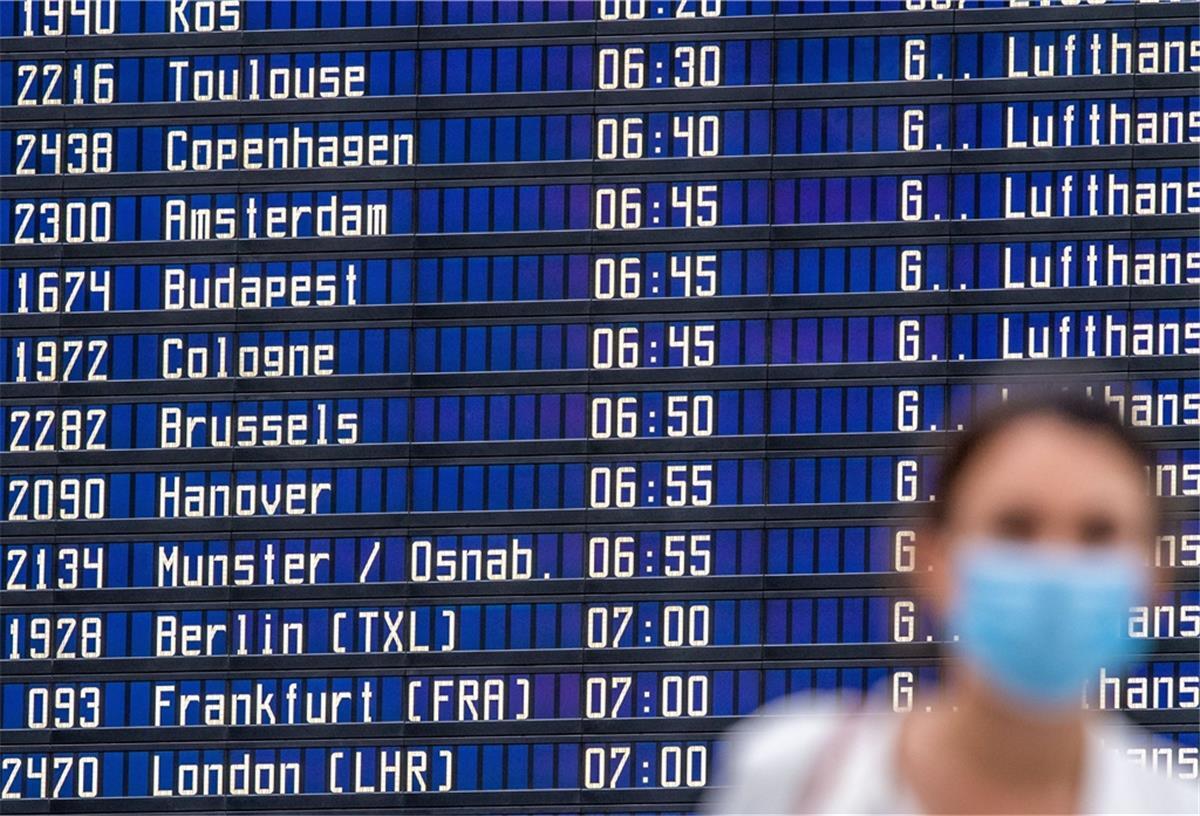 Eine Frau steht vor einer Anzeigetafel im Flughafen. 