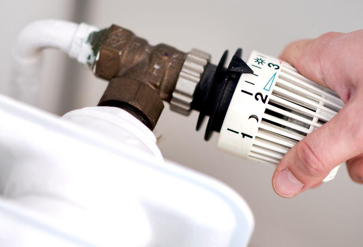 Richtig heizen und Geld sparen: Experten geben Tipps Symboldbild für Richtig heizen und Geld sparen: Ein Mann dreht das Thermostat an einem Heizkörper auf.