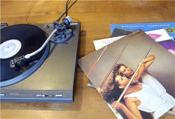 Schallplatten liegen neben einem Plattenspieler.