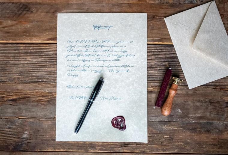 Testament hinterlegen: So sicherst Du Deinen letzten Willen richtig ab Ein beschriebenes Blatt Papier liegt mit einem Füller auf einem Holztisch.
