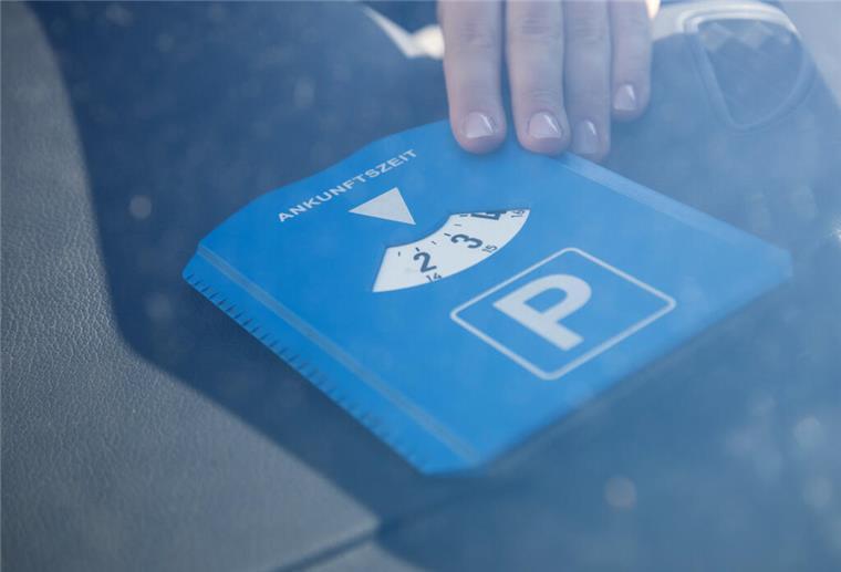 In einem Auto liegt eine blau-weiße Parscheibe.