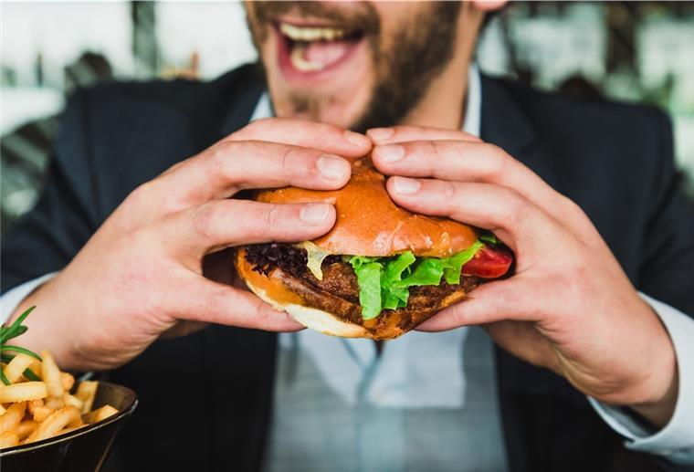 Pandemie und Klimawandel ändern das Essverhalten langfristig Ein Mann isst einen Burger.