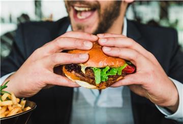 Ein Mann isst einen Burger.