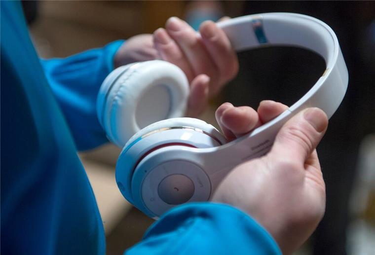 Viele wissen es nicht: Wer laut Musik hört, riskiert mehr als ein Bußgeld Ein Junge hält Kopfhörer in der Hand.