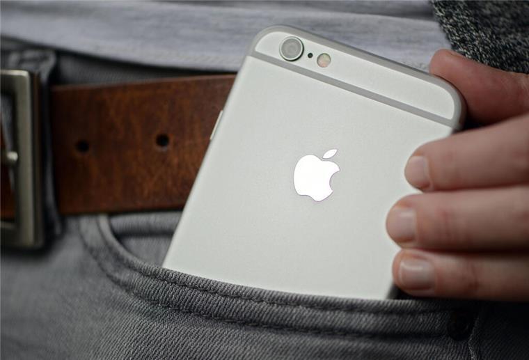 Immer mehr fälschlich ausgelöste Notrufe durch Handys Eine Frau steckt sich ein iPhone der Firma Apple in die Hosentasche.