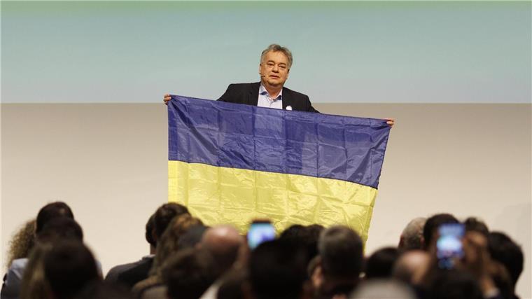 Lechner fordert Lieferung weitreichender Waffen an Ukraine Werner Kogler (Grüne), Vizekanzler von Österreich, steht mit einer Fahne der Ukraine auf der Bühne beim Bundeskongress seiner Partei, am zweiten Jahrestag der russischen Invasion.