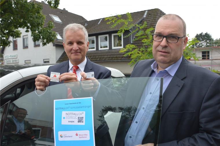 Wespa-Generalbevollmächtigter Bernd Meenzen (links) hält den Aufkleber für die Windschutzscheibe, Bürgermeister Thorsten Krüger die Plastikkarte mit dem Notfall-QR – beides kann im Ernstfall helfen, den Rettern schnelle Informationen über den jeweils Verunglückten zu liefern.