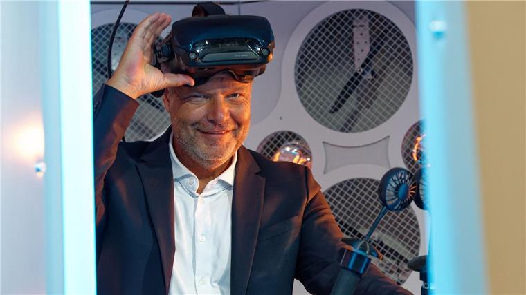 Wirtschaftsminister Robert Habeck (Grüne) steht bei einem Messerundgang bei der Computerspiele-Messe Gamescom 2022 in einem Simulator und trägt dabei eine Virtual-Reality-Brille.