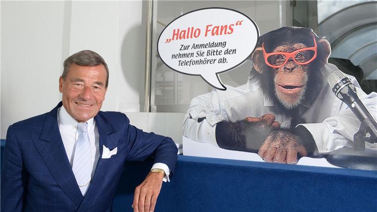 Trigema-Affe bald neu gestylt im Fernsehen Wolfgang Grupp senior mit einem Werbeschild, auf dem der bekannte Werbe-Affe „Charly“ abgebildet ist.