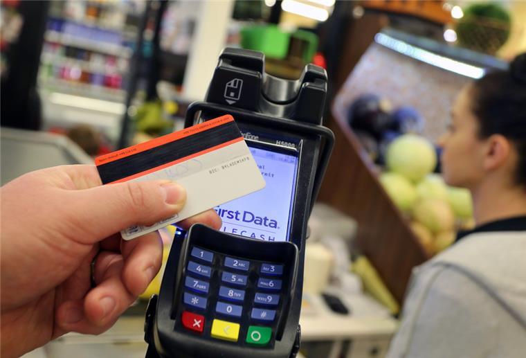 Störung von Zahlungs-Terminals im Einzelhandel hält an Eine Karte wird an den Bezahl-Terminal an der Kasse eines Supermarktes gehalten.