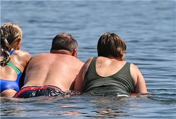 Eine Familie schwimmt auf einer Luftmatratze im Wasser eines Sees.