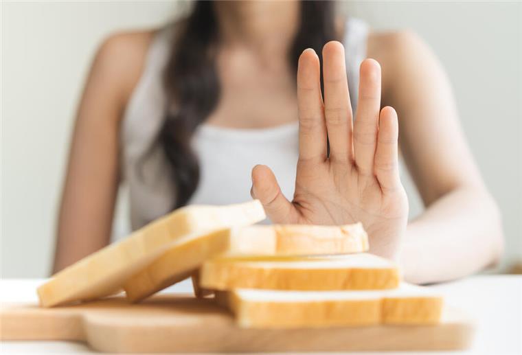 Zöliakie: Wenn Getreide krank macht Eine Frau macht eine ablehnende Handbewegung in Richtung eines Stapels mit Toastbrotscheiben.
