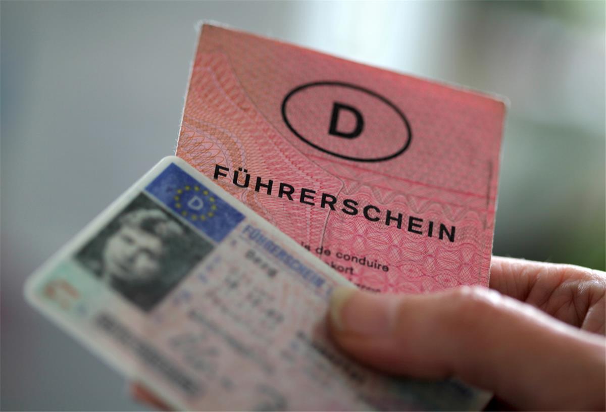 Zwei Führerscheine verschiedener Generationen hält eine Frau in der Hand