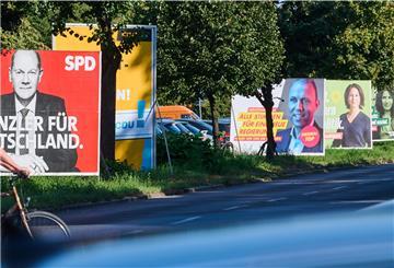 Wahlplakate verschiedener Parteien am Straßenrand.