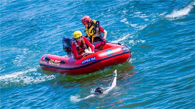 Zwei DLRG-Rettungsschwimmerinnen ziehen bei einer Rettungsübung eine Frau aus dem Wasser der Ostsee.
