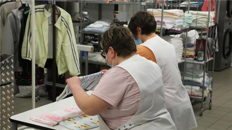 Weniger Arbeitslose mit Handicap - nur kurze Erholung? Zwei Frauen arbeiten in der Wäscherei der Lebenshilfe Gera e.V und legen dort Wäsche zusammen.
