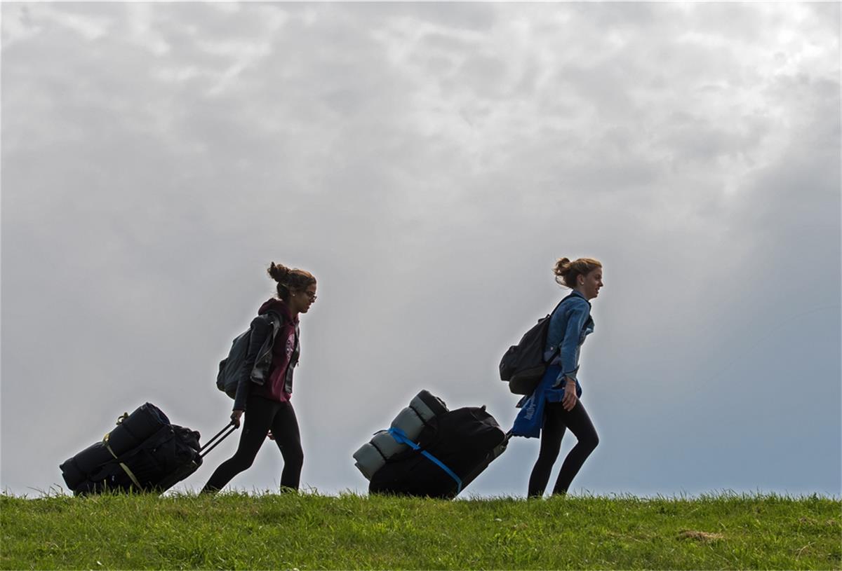 Norddeutsche möchten ihren Urlaub 2020 vor allem im Norden verbringen Zwei junge Frauen ziehen ihre Koffer über einen Deich.