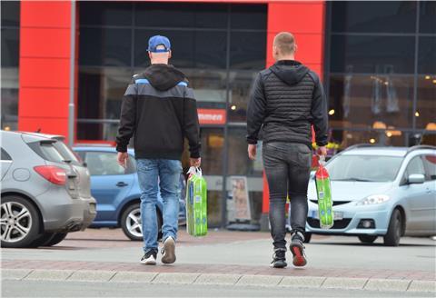 Zwei junge Männer tragen Toilettenpapier über den Parkplatz eines Zevener Supermarktes. In diesen Zeiten kein selbstverständliches Bild.
