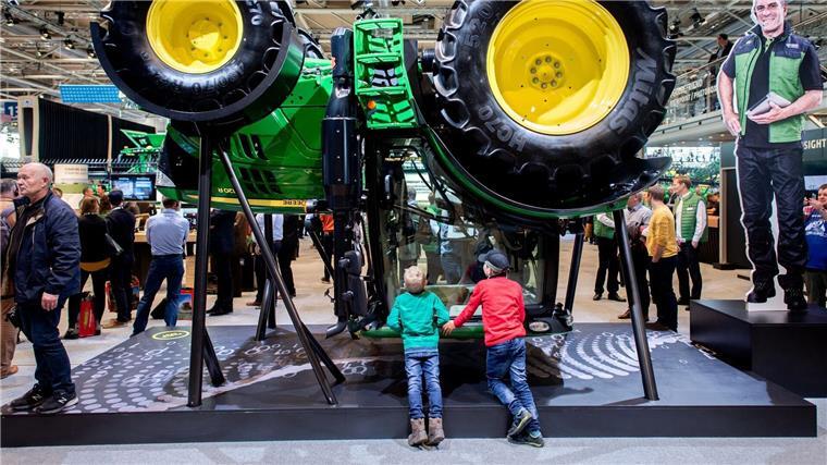 Zwei Jungen betrachten am Stand von John Deere auf der Landtechnik-Messe einen Traktor.