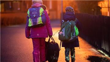 Zwei Schüler gehen am frühen Morgen auf dem Schulweg zu ihrer Grundschule in der Region Hannover.