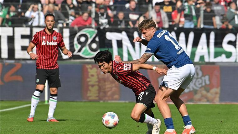 Zweikampf um den Ball: Hayate Matsuda (Hannover 96) wird von Joel Grodowski (Arminia Bielefeld) bedrängt.